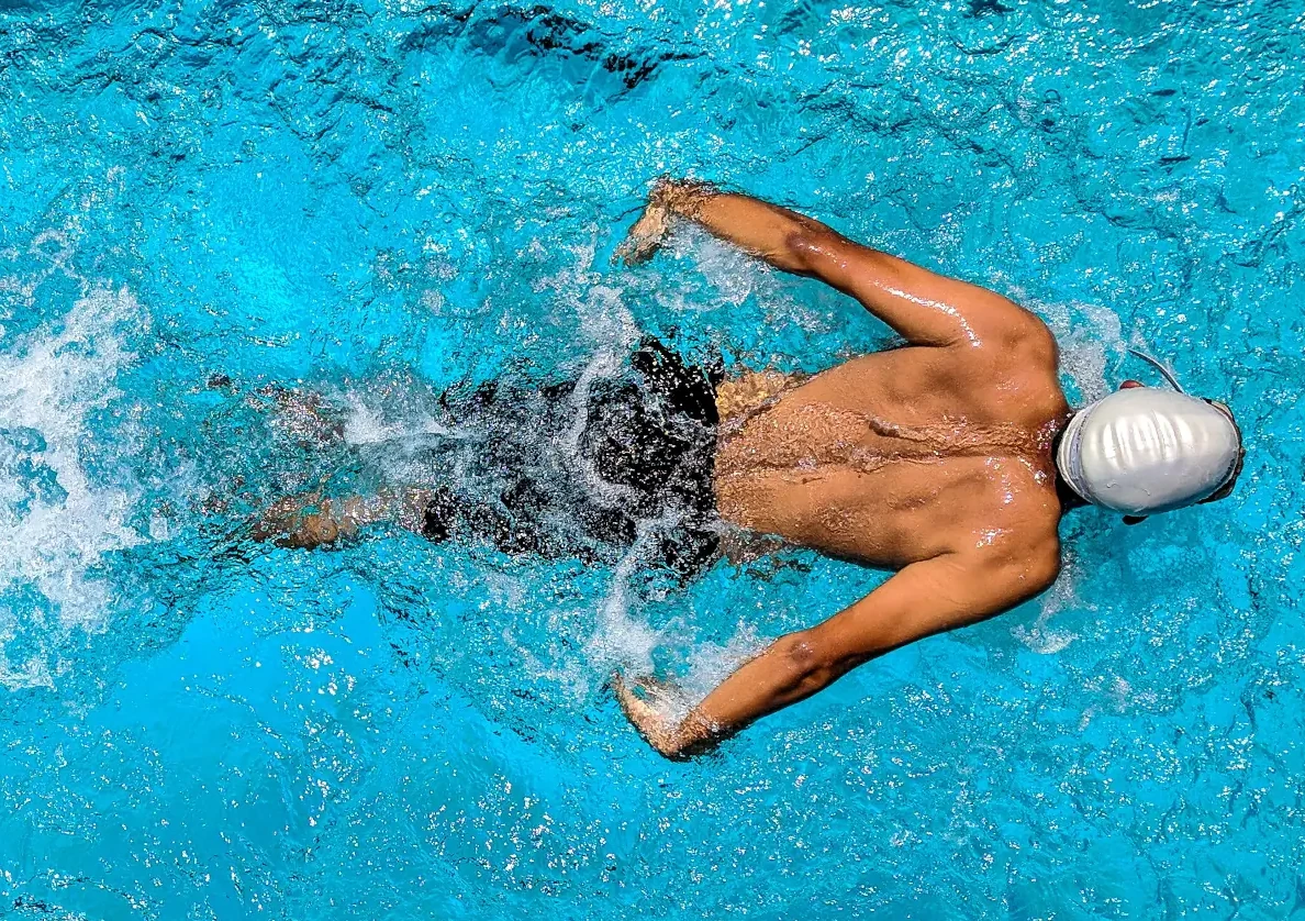 Overhead view of a swimmer in a sunlit turquoise pool